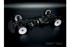 RC Maker SP2 EP 1/10 electric touring car chassis kit featuring carbon fibre components and white wheels on a dark background.