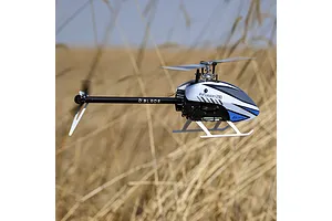 Blade InFusion 210 RC helicopter in flight outdoors against a blurry dry grass field background.