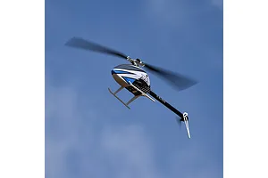 Blade InFusion 210 RC helicopter in flight against a clear blue sky, showing its white, blue, and black color scheme with spinning rotor blades.
