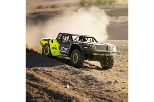 Losi 1/5 scale short course RC truck driving through dirt kicking up dust in an outdoor setting.