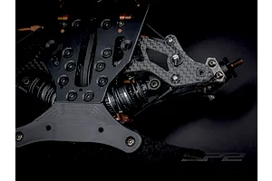 Close-up studio view of the carbon fiber suspension and chassis components of the RC Maker SP2 1/10 scale touring car kit.