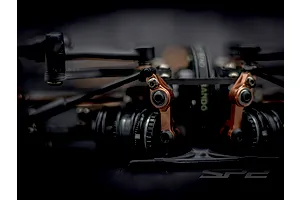 Close-up shot of the steering mechanism and bronze-coloured linkages on the RC Maker SP2 touring car kit chassis.
