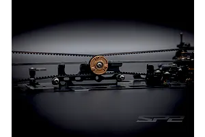 Close-up of the internal chassis belt drive and central bronze pulley of the RC Maker SP2 touring car kit.