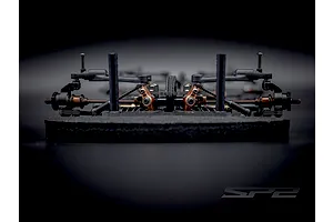 Close-up front-on view of the RC Maker SP2 EP RC touring car chassis highlighting suspension components and foam bumper.
