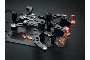 Close-up of black and copper anodised aluminium RC car chassis components and bulkheads on a dark background.