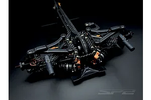 Close-up studio shot of the front suspension and chassis assembly of an RC Maker SP2 EP touring car kit.