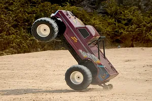 FMS Ford F-100 High Roller RC Monster Truck performing a wheelie on a dirt track outdoors.