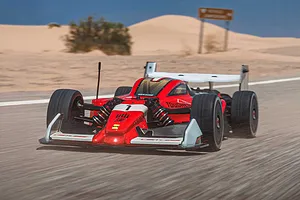 ARRMA Limitless 120 Street Speed RC car driving fast on a paved desert road with sandy dunes in the background.