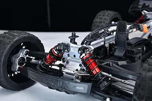 Close-up of a red aluminium front shock tower installed on an RC car chassis with red and black shock absorbers.