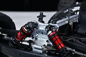 Close-up of a red and silver GPM aluminium front shock tower installed on an RC vehicle chassis with red shocks.