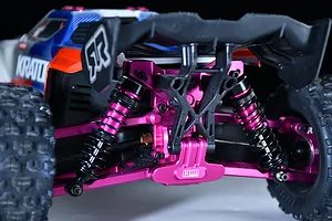 Close-up of an installed purple aluminium rear bumper on an RC car chassis with shock absorbers, a wing mount, and suspension arms.