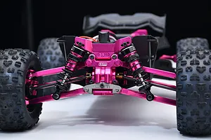 Close-up of the front suspension and pink anodized aluminium parts installed on an RC car chassis.