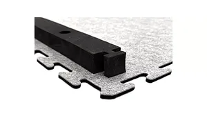Close-up of interlocking grey carpet track tile with a black track barrier attached.