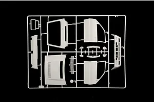 A white plastic model kit sprue containing car parts like body panels and doors against a black background.