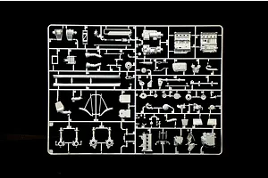 Grey plastic model kit parts sprue containing engine blocks and mechanical components on a black background.