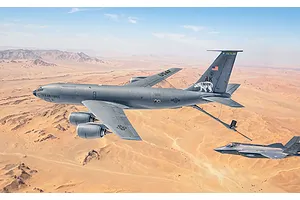 A US Air Force KC-135 Stratotanker flying over a desert landscape with another fighter aircraft nearby.