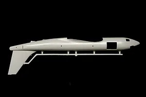 Molded plastic model airplane fuselage attached to a parts sprue against a dark background.