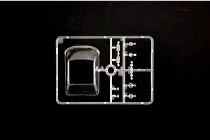Clear plastic model kit sprue containing windows and transparent parts for a 1/24 scale car model against a black background.