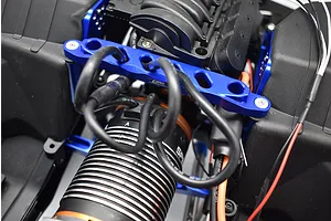 GPM blue aluminium front chassis brace installed on an RC vehicle chassis with black motor and wires.