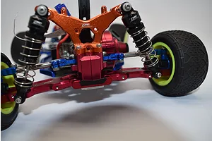 Close-up rear view of an RC buggy chassis installed with aftermarket anodized aluminum upgrade parts including shock tower, suspension arms, and links.