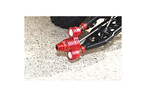Close-up of an orange anodized aluminium steering hub installed on an RC car suspension assembly.