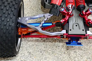 Close-up of installed red aluminium turnbuckles and suspension upgrades on an RC model car chassis.