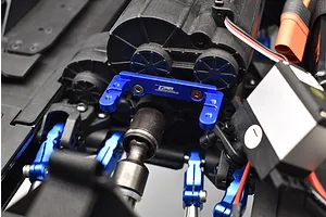 Close-up of a blue aluminium transmission servo mount installed on an RC car chassis near the transmission and servo.