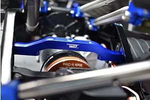 GPM aluminium front lower chassis brace installed in an RC car chassis, featuring a bright blue anodized finish and white laser-etched branding.