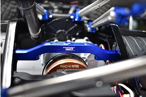 GPM blue aluminium front lower chassis brace installed on an RC vehicle chassis near the motor.