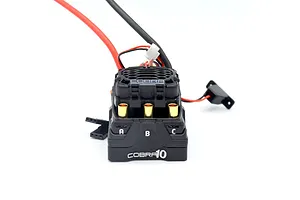 Castle Creations Cobra 10 ESC shown from the front angle with visible golden bullet connectors and wiring against a white background.