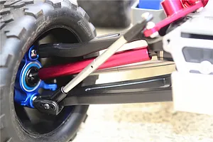 Close-up view of an RC car suspension assembly installed with a red alloy link and a silver drive shaft.