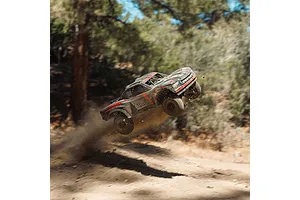 ARRMA MOJAVE 6S EXB RC desert truck jumping through the air on an outdoor dirt track with dust flying.