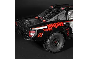 Close-up rear quarter view of the ARRMA MOJAVE 6S EXB RC desert truck in black, highlighting rear body details, roll cage, and textured tire.