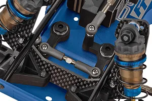 Close-up studio view of the steering assembly and carbon fiber shock tower on a Team Associated RC hobby car chassis.