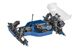 Team Associated RC car chassis kit displayed on a plain white background, featuring blue anodized aluminium parts, carbon fiber shock towers, and an unpainted rear wing.