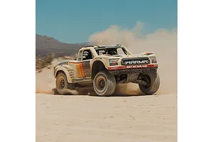 ARRMA MOJAVE 6S RC short course truck driving fast through a dusty desert landscape, kicking up sand.