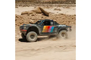 ARRMA MOJAVE 6S RC short course truck driving through a dusty dirt terrain outdoors