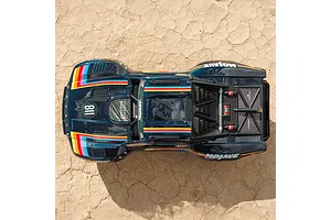 Top-down view of the blue ARRMA Mojave 6S RC short course truck parked on dry cracked earth ground.