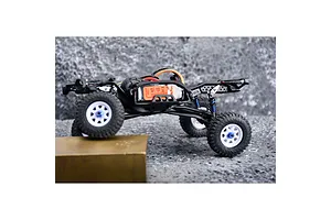 Side profile of an RC crawler chassis with blue flex blade extensions installed on the suspension.