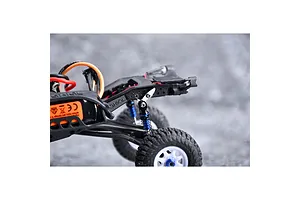 Close-up view of an RC crawler chassis installed with aluminium flex blade extensions on the rear suspension.