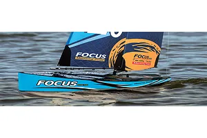 Close-up action shot of the Joysway Focus V3 RC sailboat navigating across rippled water outdoors.