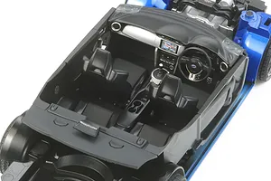 High-angle view of the detailed black interior of a 1/24 scale Tamiya Subaru BRZ model kit, showing seats, dashboard, and steering wheel.