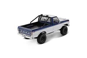 Rear-three-quarter studio shot of the blue and white FMS FCX18 II Ford F-100 RC rock crawler showing truck bed and roll bar.