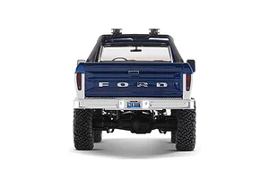 Rear view of the FMS FCX18 II Ford F-100 RC rock crawler in blue and white, showing tailgate details, bumper, and tires against a white background.
