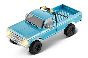 High angle view of a cerulean blue FMS FCX18 Ford F-100 RC rock crawler with lit headlights and roll bar.