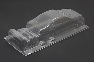 Unpainted clear polycarbonate RC car body shell with additional molded parts in a studio setting against a dark background.