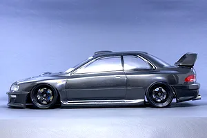 Side profile view of a dark grey RC drift car body styled as a Subaru Impreza 22B STi mounted on a chassis with black wheels.