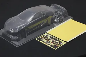 Clear unpainted polycarbonate 1/10 scale RC car body shell with separate parts, decal sheet, and window mask.