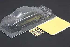 Clear unpainted polycarbonate RC car body shell with a mask sheet and decal sheet on a dark surface.