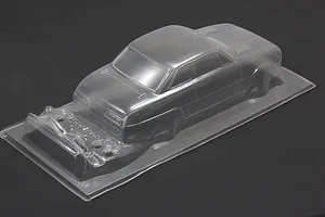 Unpainted clear polycarbonate RC car body shell with additional molded accessory parts on a dark background.